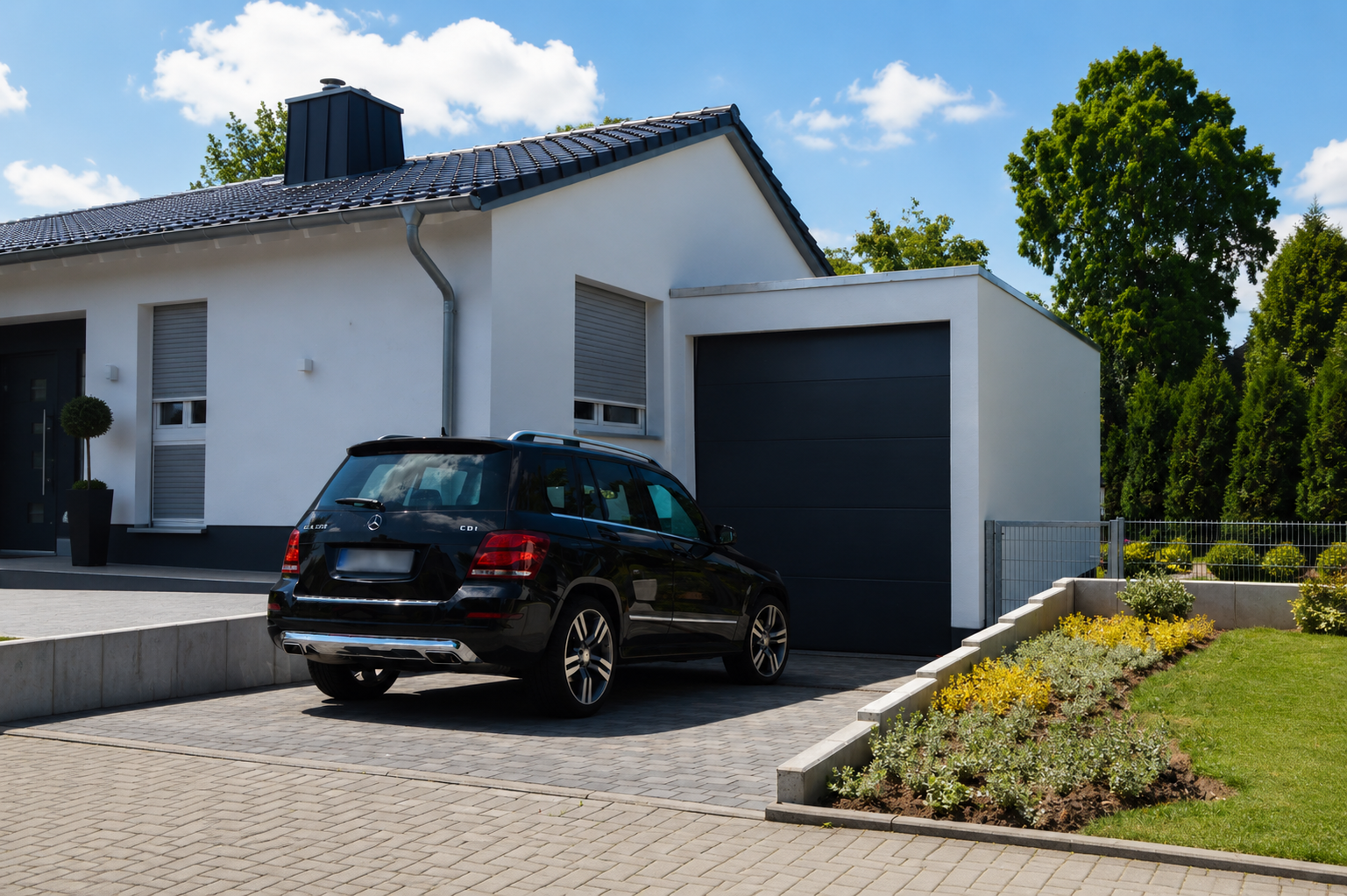 Modern woonhuis met zwarte SUV op bestrate oprit. Verzorgde tuin.