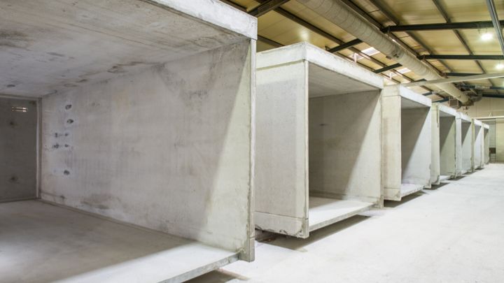 Rij betonnen elementen in een magazijninterieur, ruwbouw, zichtbare plafondinstallaties.