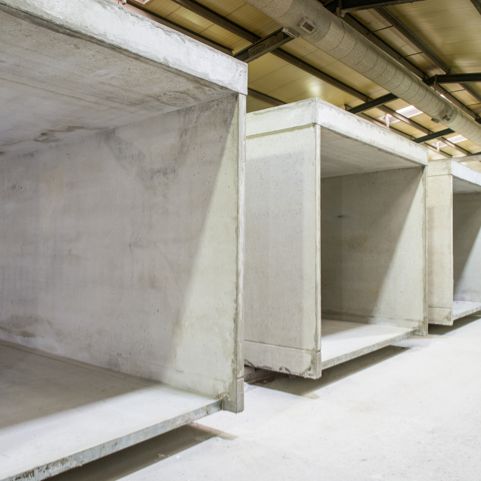 Rij betonnen elementen in een magazijninterieur, ruwbouw, zichtbare plafondinstallaties.