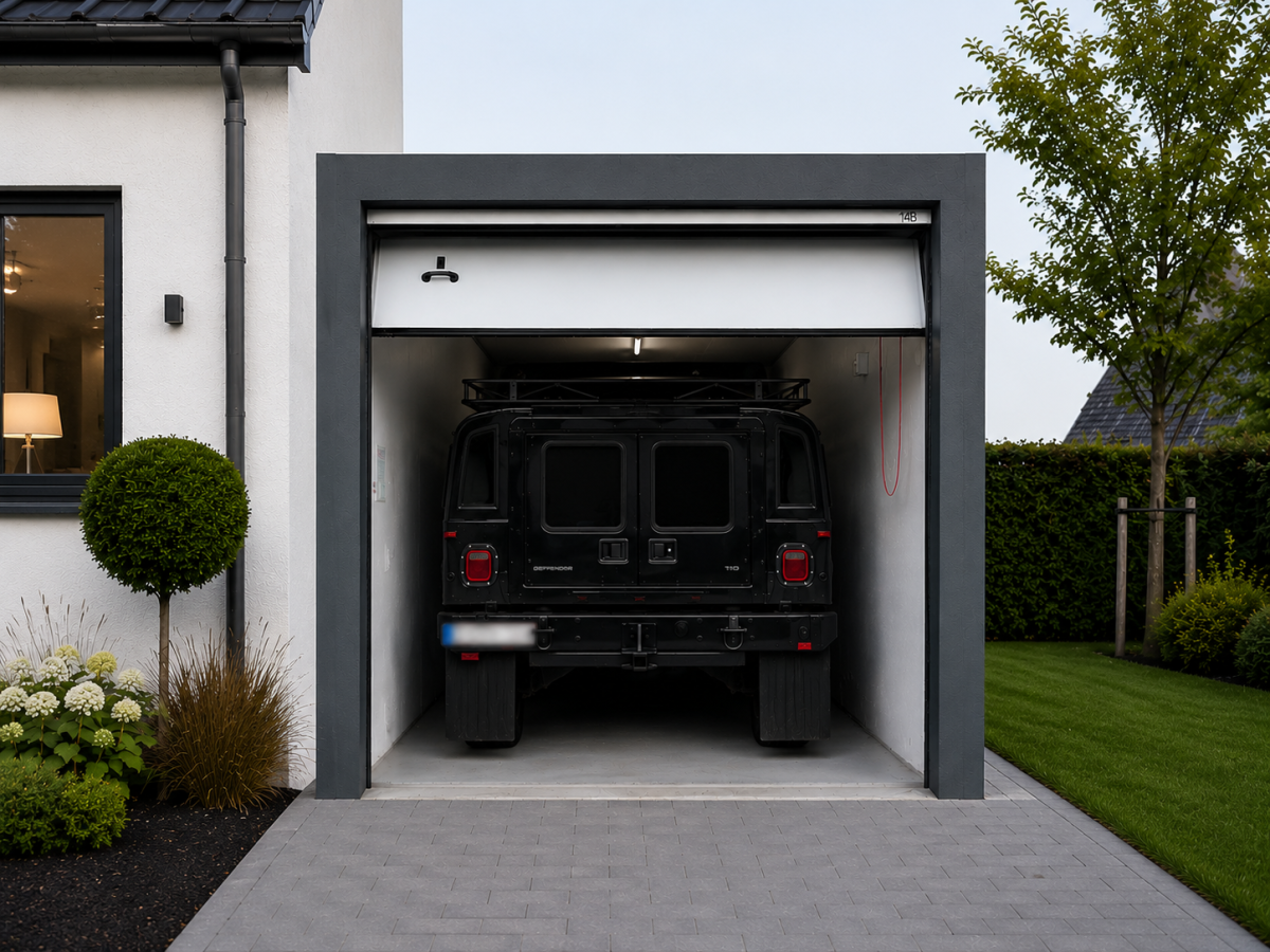 Zwarte off-road auto in de open garage van een modern huis. Voortuin met heg en struiken.