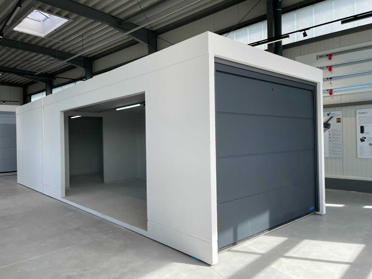 Interieur van een witte, rechthoekige garage met open rolpoort. Op de achtergrond andere garages en een dakraam.