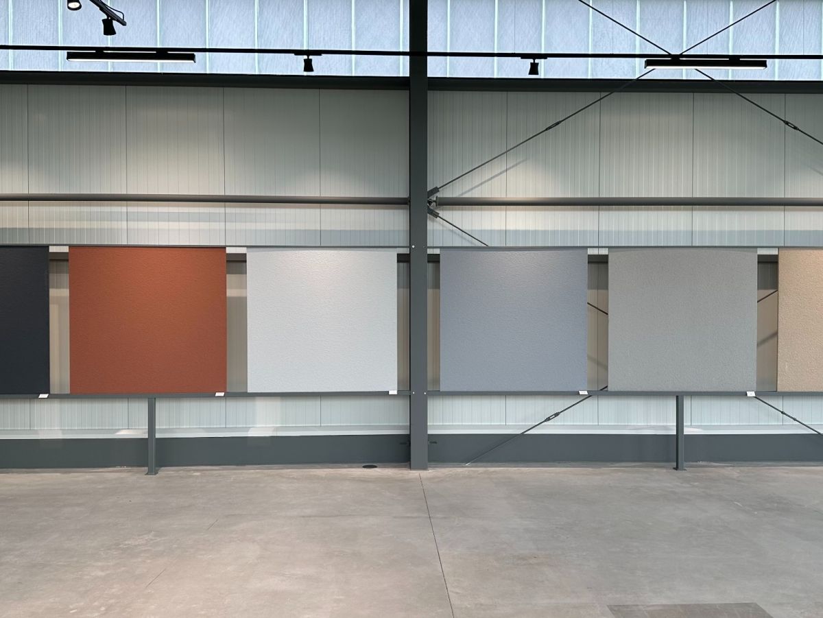 Grote ruimte met metalen structuur en zeven kleurstalen aan de wand.