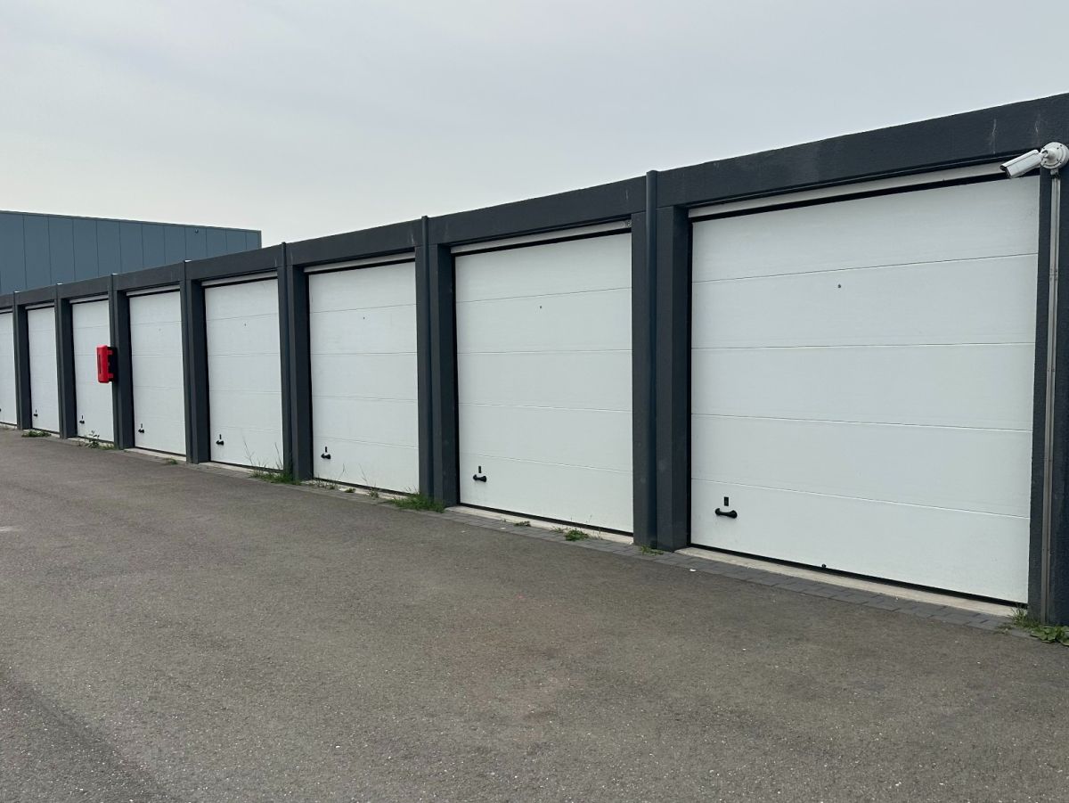 Rij witte garagedeuren met zwart frame, voor asfalt oppervlak.