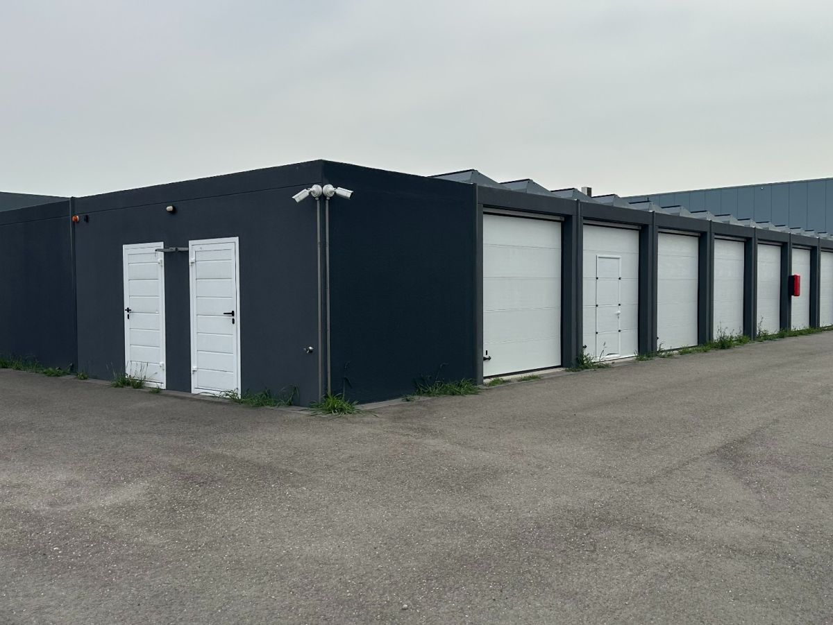 Rij zwarte garages met witte deuren op een grijze dag.