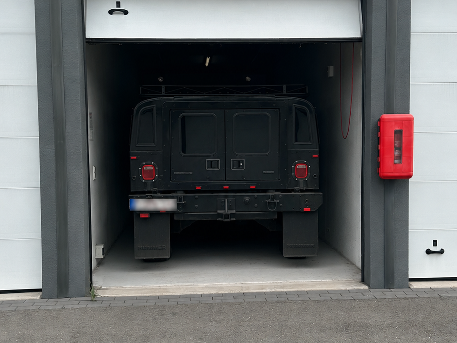 Donkere off-road auto rijdt een garage in. Links en rechts verdere garages.