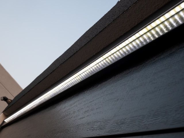 Donkere houten gevel met een heldere LED-strip onder de dakoversteek.
