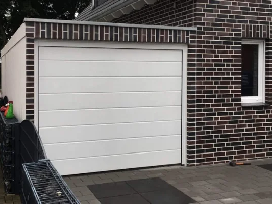 Modern huis met witte garage en donker metselwerk. Raam rechts van de garage.