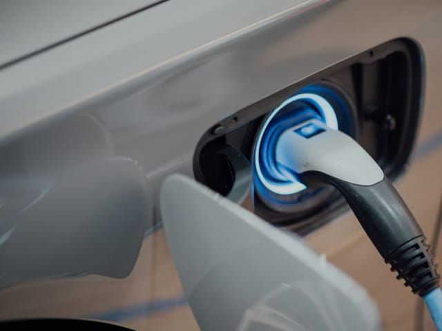 Elektrische auto wordt opgeladen. Aansluitverbinding met blauw verlichte stekker.