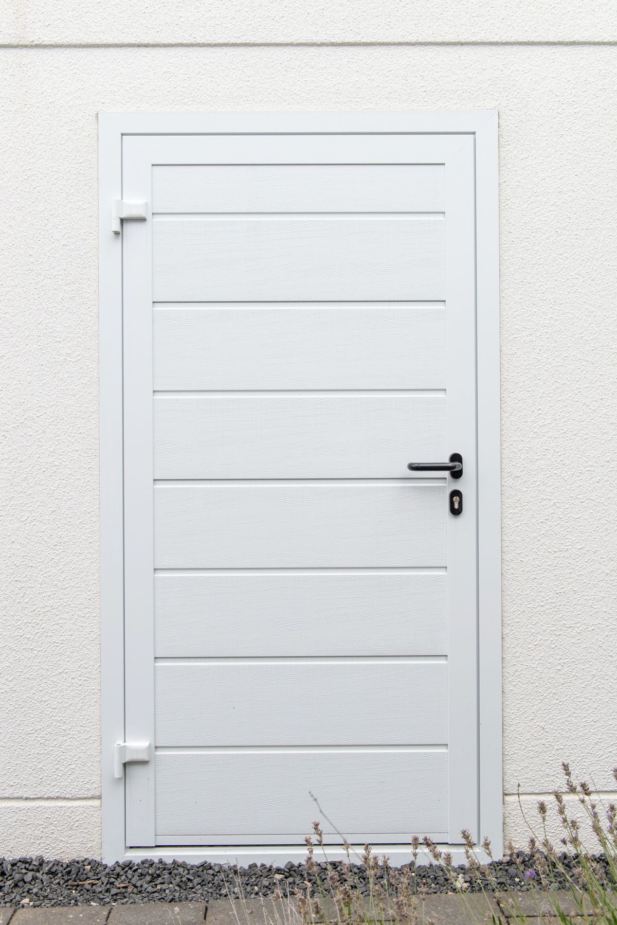 Witte deur met horizontale panelen in een lichte prefab garage, toont een praktische zijdeur voor extra toegang.