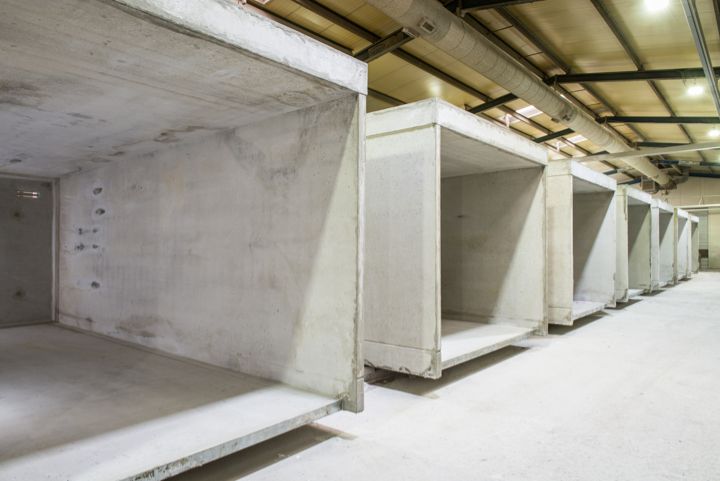 Rij betonnen elementen in een magazijninterieur, ruwbouw, zichtbare plafondinstallaties.