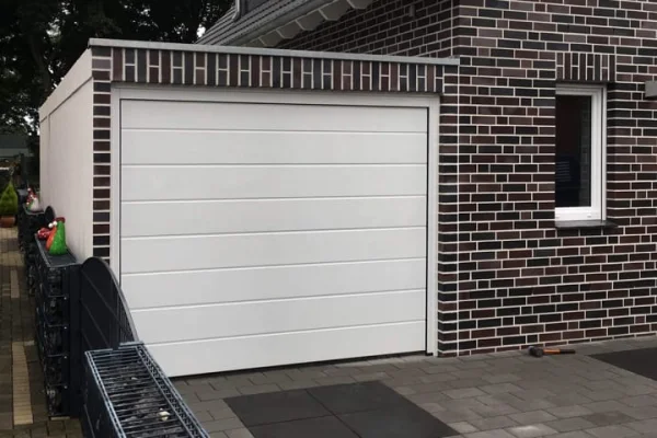 Modern huis met witte garage en donker metselwerk. Raam rechts van de garage.